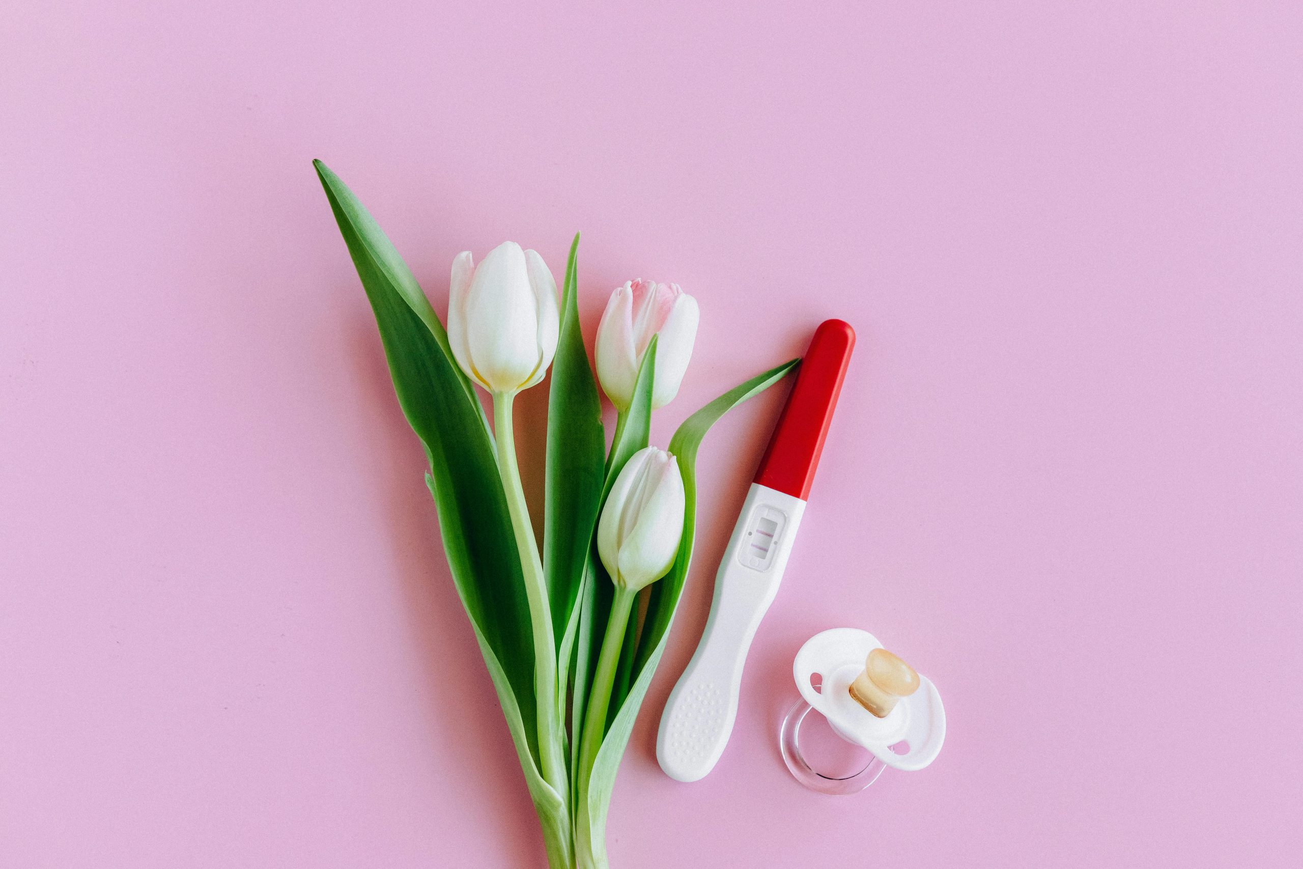 Flowers next to a pregnancy test and a pacifier