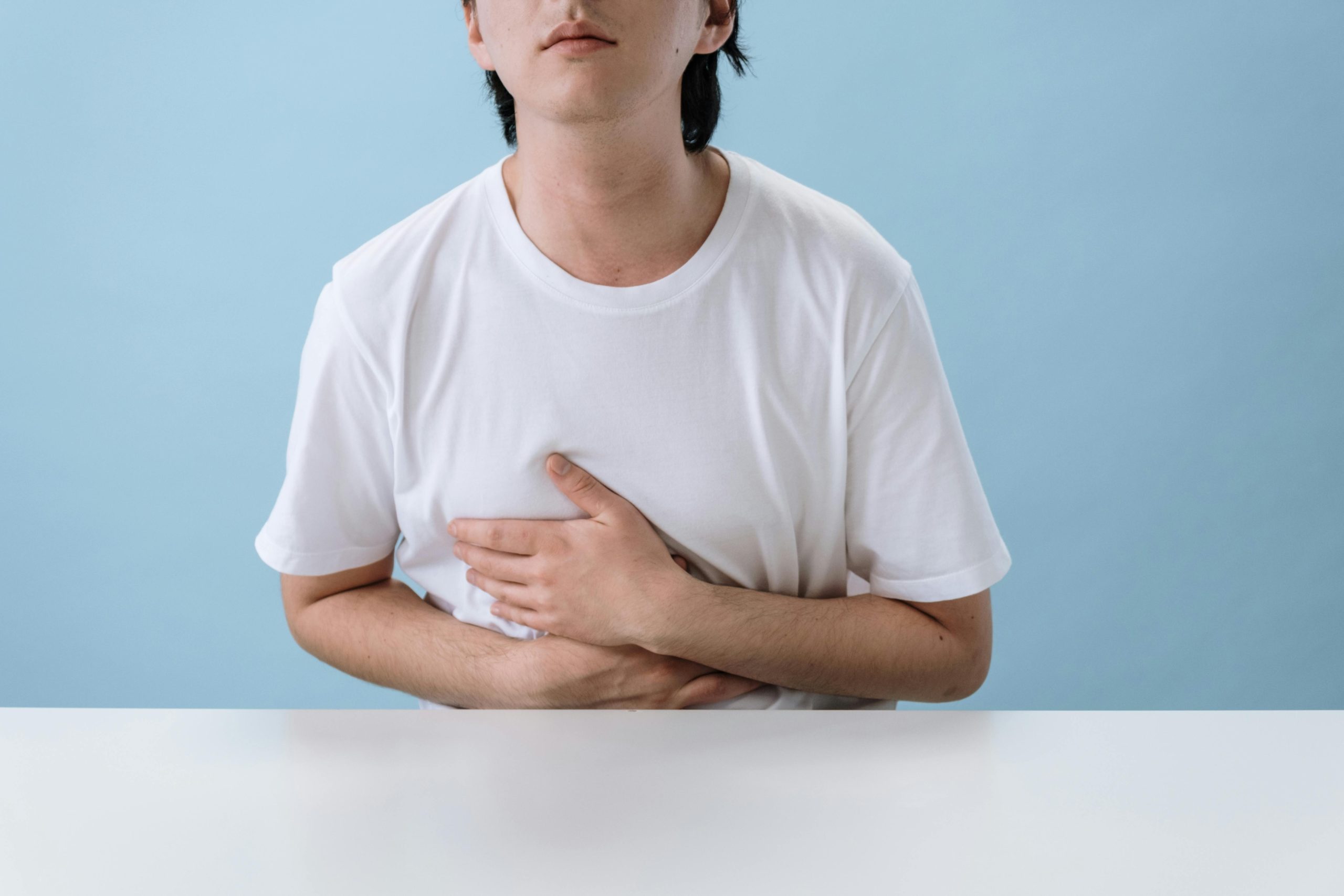 Person holding there stomach while sitting at a table
