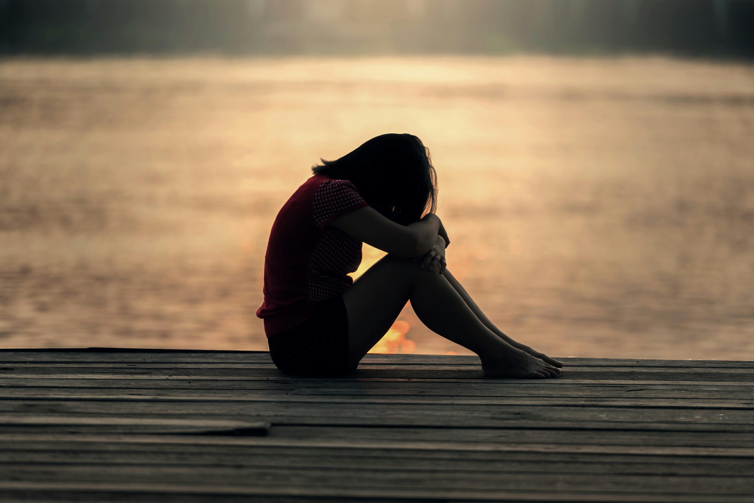 Person sitting on a dock with their head down