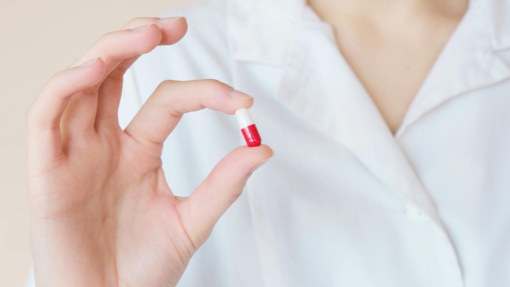 Doctor holding a red and white pill