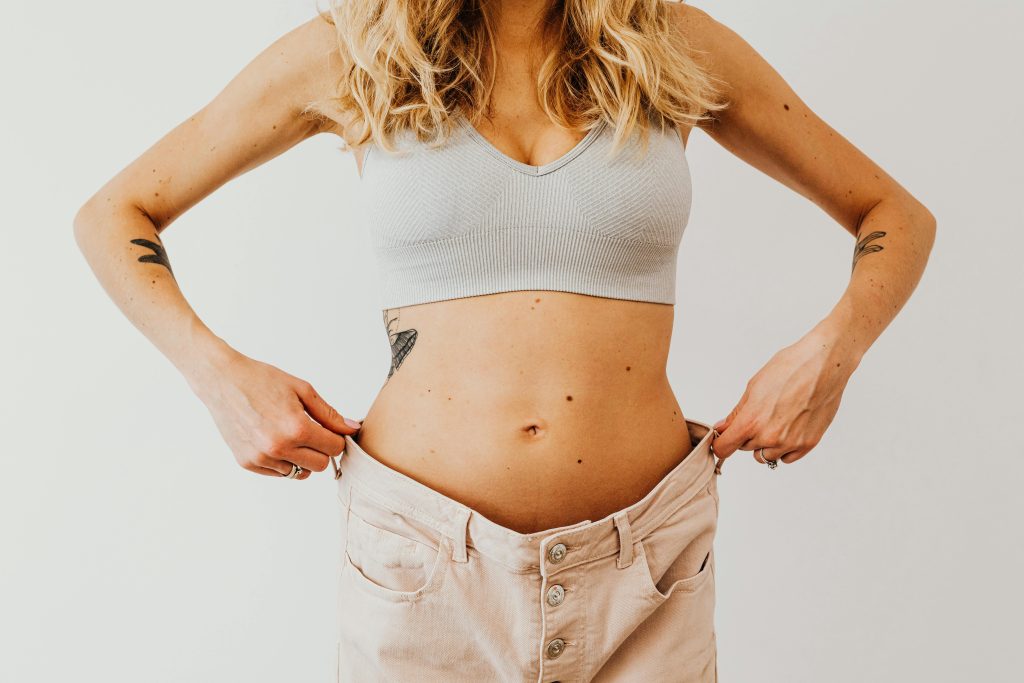 Woman pulling up pants that are too big from weight loss